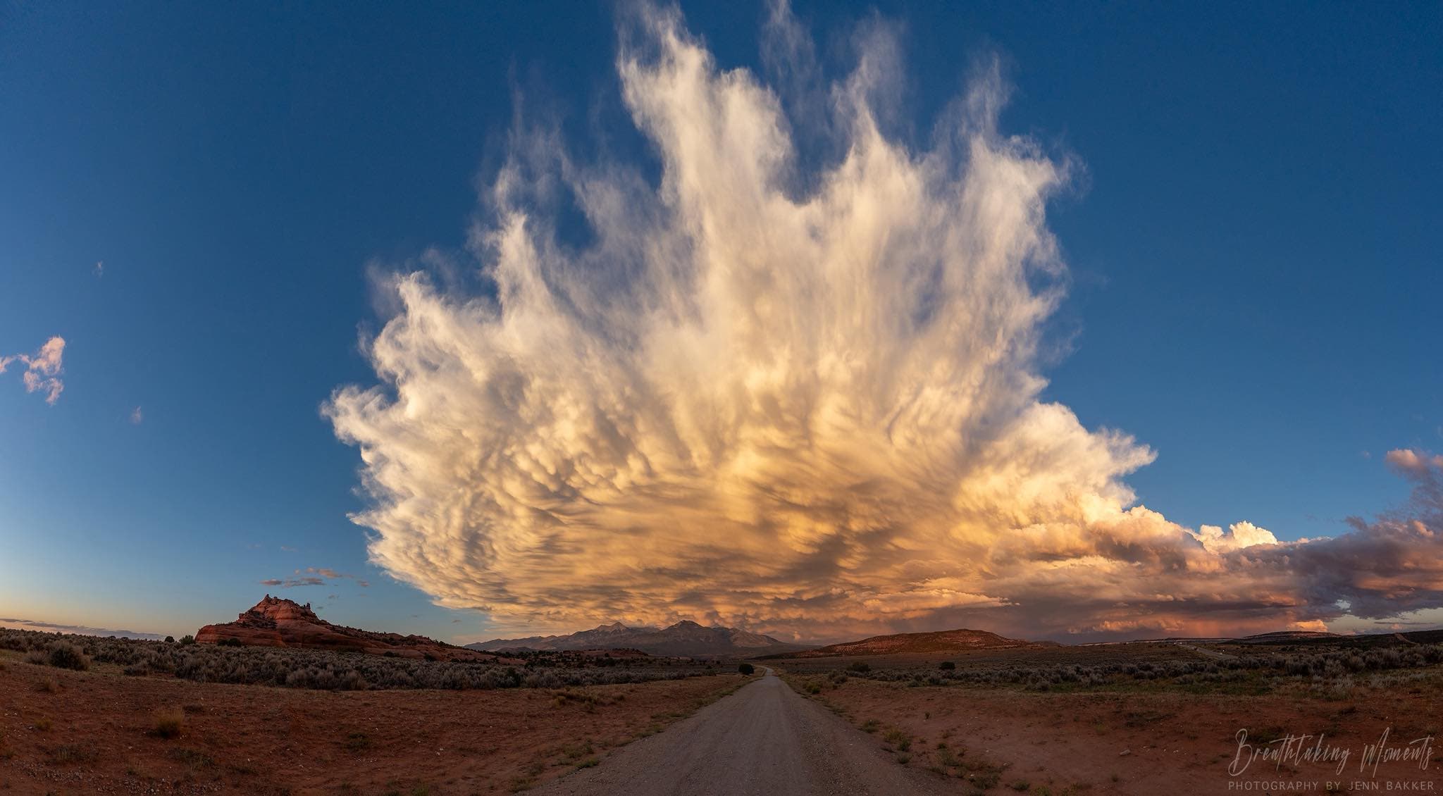 Massive cumulonimbus storm cloud exploding over a desert road at sunset near Moab Utah
